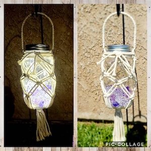 May include: A clear glass jar with a silver lid, suspended by a macrame holder. The jar is filled with purple and clear decorative stones and illuminated by a soft light. A white tassel hangs from the bottom.