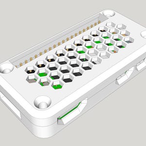 May include: A white rectangular protective case for a single-board computer, featuring a honeycomb-patterned top surface that reveals a green circuit board underneath, along with exposed gold-colored connector pins and side port openings.