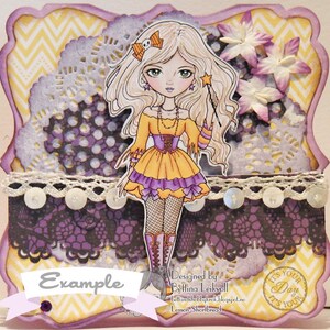 May include: A purple and yellow card with a whimsical illustration of a girl with blonde hair, wearing a yellow dress and holding a wand. The card has a lace border and a scalloped edge. The text "Example" is printed on the card. The text "Designed by Bettina Leikvoll" is printed on the card. The text "It's Your Day It's Your Day" is printed on the card.