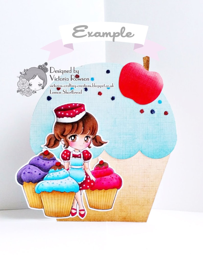 K&ouml;nnte beinhalten: Eine 3D-Cupcake-Karte mit einem M&auml;dchen in einem rot-wei&szlig;en Kleid und einer rot-wei&szlig;en M&uuml;tze, das auf drei Cupcakes sitzt. Die Cupcakes sind lila, blau und rosa. Die Karte ist mit einem roten Apfel, blauem und rotem Glitzer sowie dem Text "Designed by Victoria Rowson" und "Lemon Shortbread" verziert.