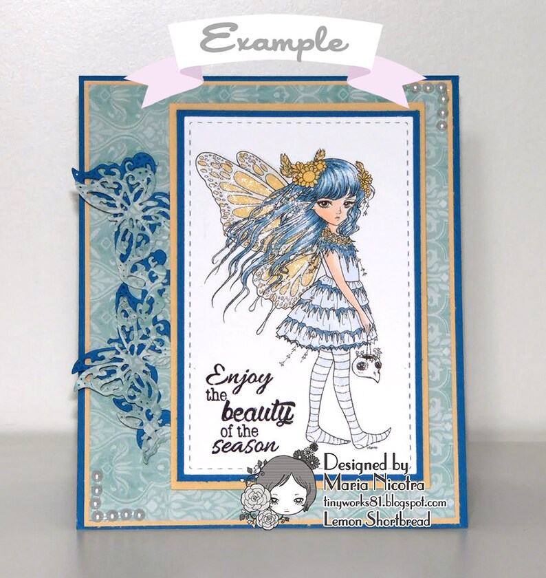 May include: A blue and white card featuring a fairy illustration and the text "Enjoy the beauty of the season". The card is decorated with blue butterflies and pearls.