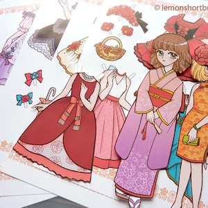 Puede incluir: Un conjunto de mu&ntilde;ecas de papel con cuatro atuendos diferentes. Los atuendos incluyen un vestido rojo con una superposici&oacute;n de encaje blanco, un vestido rosa con una superposici&oacute;n de encaje blanco, un kimono rosa con flores blancas y un vestido amarillo con una superposici&oacute;n de encaje blanco. Las mu&ntilde;ecas de papel son todas femeninas y tienen el pelo largo.