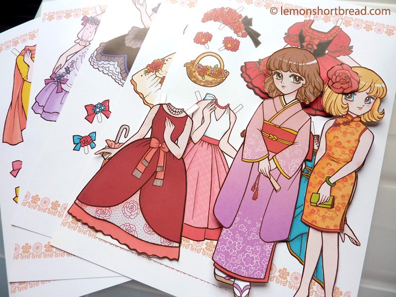 Puede incluir: Un conjunto de mu&ntilde;ecas de papel con cuatro atuendos diferentes. Los atuendos incluyen un vestido rojo con una superposici&oacute;n de encaje blanco, un vestido rosa con una superposici&oacute;n de encaje blanco, un kimono rosa con flores blancas y un vestido amarillo con una superposici&oacute;n de encaje blanco. Las mu&ntilde;ecas de papel son todas femeninas y tienen el pelo largo.