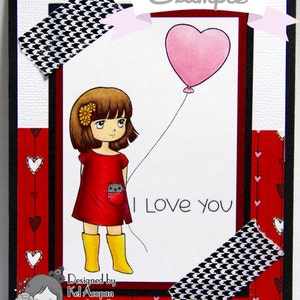 May include: A red and white card with a black and white checkered pattern on the top and bottom. The card features a cartoon girl holding a pink heart-shaped balloon. The text "I Love You" is written on the card. The card is designed by Kel Acopan.