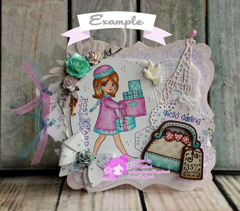 K&ouml;nnte beinhalten: Eine wei&szlig;e Karte mit einer rosa und blauen Illustration einer Frau, die Geschenke tr&auml;gt. Die Karte hat einen wei&szlig;en Spitzenrand und eine wei&szlig;e Eiffel-Turm-Ausschneidung. Der Text "hello darling" steht auf der Karte.