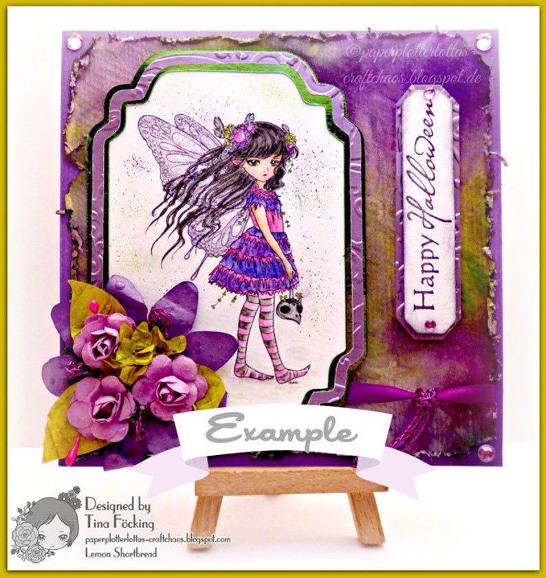 May include: A purple and green Halloween card featuring a fairy holding a skull. The card has a banner that reads "Example" and the text "Happy Halloween" on the right side. The card is designed by Tina F".cking and is called "Lemon Shortbread".