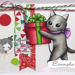 May include: A gray cat with a purple bow carrying a red and green gift box with a green bow. The background is a white card with a red and green candy cane pattern. The text "Designed by Kel Acopan scrap-photocrafts.com Lemon Shortbread" and "Example" are also on the card.