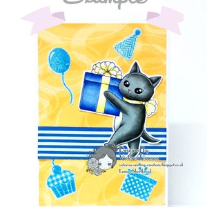 May include: A birthday card featuring a black cat holding a blue and yellow gift box. The card has a yellow background with blue and white stripes, a blue balloon, a blue and white cupcake, and a blue and white party hat. The card also includes the text "Designed by Victoria Rowson" and "victorias-crafting-creations.blogspot.co.uk Lemon Shortbread".