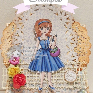 Peut inclure: Illustration num&eacute;rique d'une fille en robe bleue tenant un sac violet avec des fleurs. L'image est sur un fond de dentelle blanche avec un motif bleu clair et blanc. Le texte "Designed by Bettina Leikvoll" et "Lemon Shortbread" est visible sur l'image.