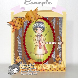 Peut inclure: Une carte faite &agrave; la main avec un fond jaune et un papier &agrave; motifs brun et gris. La carte repr&eacute;sente une fille aux cheveux bleus et une &eacute;charpe rouge, debout dans un d&eacute;cor de for&ecirc;t. La carte est d&eacute;cor&eacute;e d'un n&oelig;ud jaune et du texte "Wishing You".