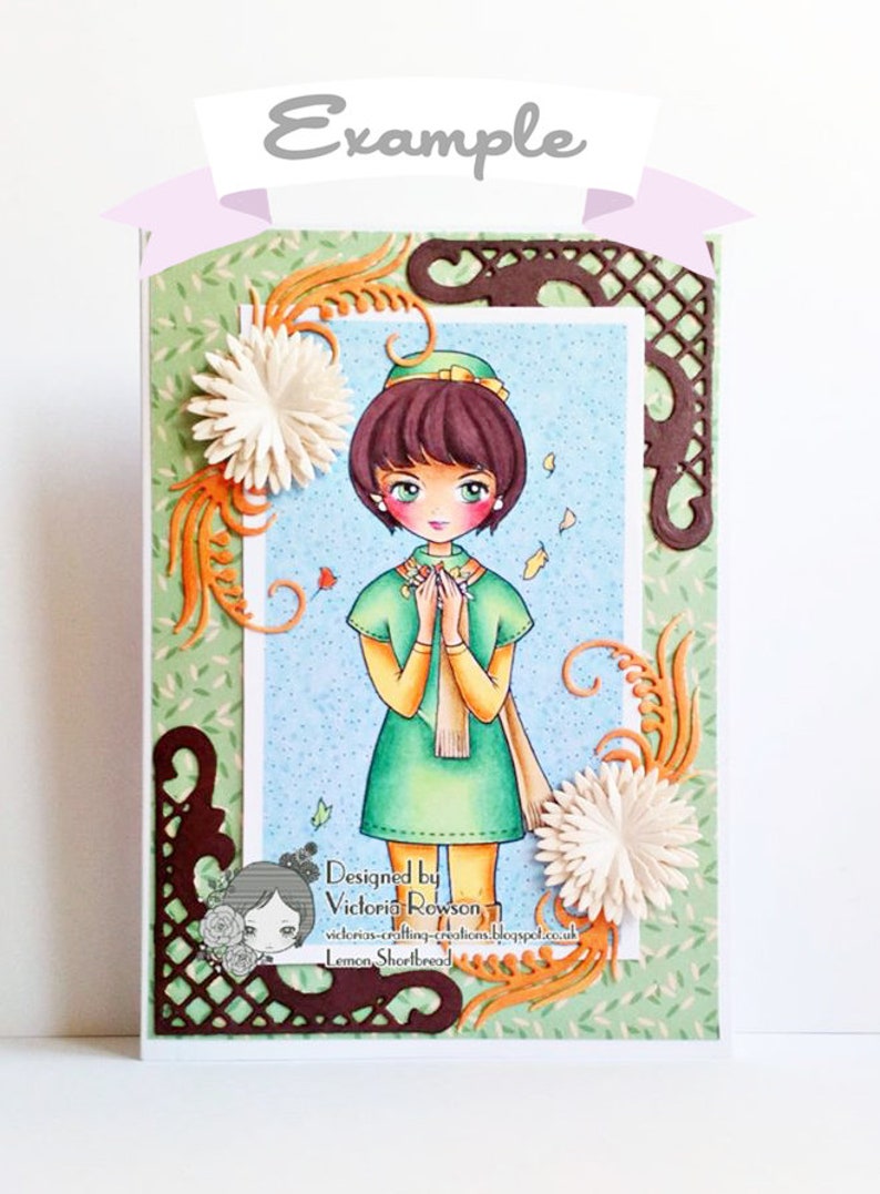 Peut inclure: Une carte faite &agrave; la main repr&eacute;sentant une fille aux cheveux bruns et &agrave; la robe verte, entour&eacute;e de feuilles d'automne et de fleurs. La carte est d&eacute;cor&eacute;e de d&eacute;coupes en papier brun et du texte "Designed by Victoria Rowson, victorias-crafting-creations.blogspot.co.uk Lemon Shortbread".