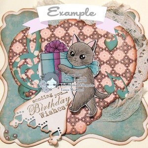 May include: A teal blue card with a white lace border and a heart-shaped design. The card features a gray cat holding a blue gift box with a purple bow. The text "sending you... Birthday Wishes" is written in brown on the card.
