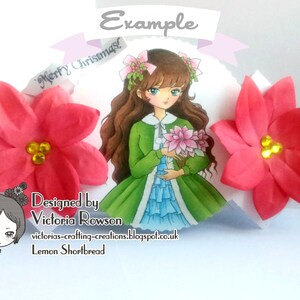 May include: A handmade Christmas card featuring a girl with brown hair and a green dress holding a bouquet of pink flowers. The card is decorated with two red poinsettia flowers and the text "Merry Christmas" and "Example".