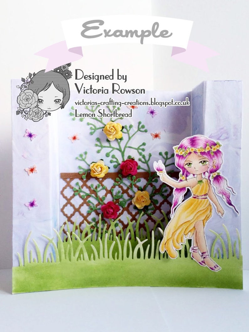 May include: A handmade card featuring a fairy with pink hair and a yellow dress standing in front of a trellis with green vines and red and yellow flowers. The card is designed by Victoria Rowson and is called "Lemon Shortbread".