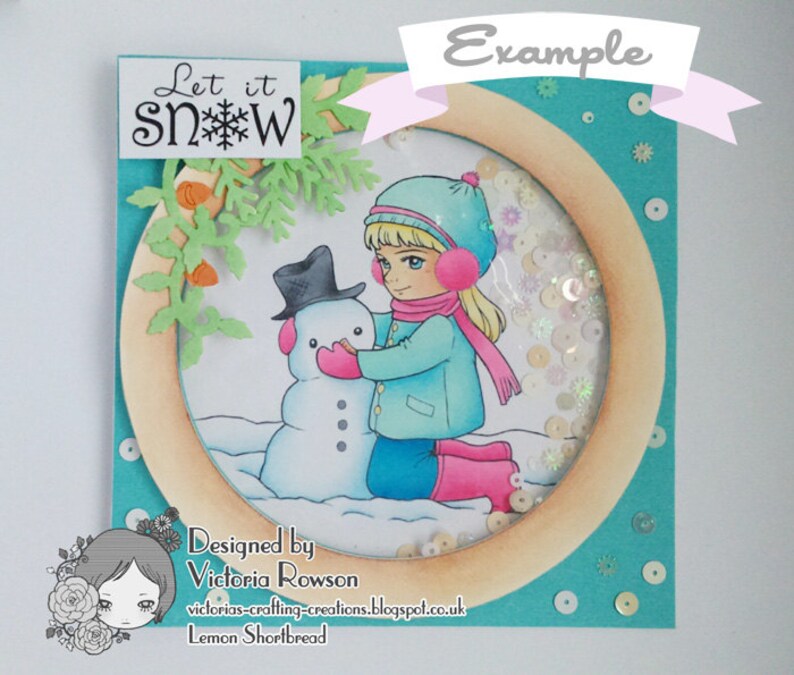 May include: A handmade card with a turquoise background and a circular cutout featuring a girl in a blue coat and pink hat building a snowman. The text "Let it snow" is on the top left corner of the card.