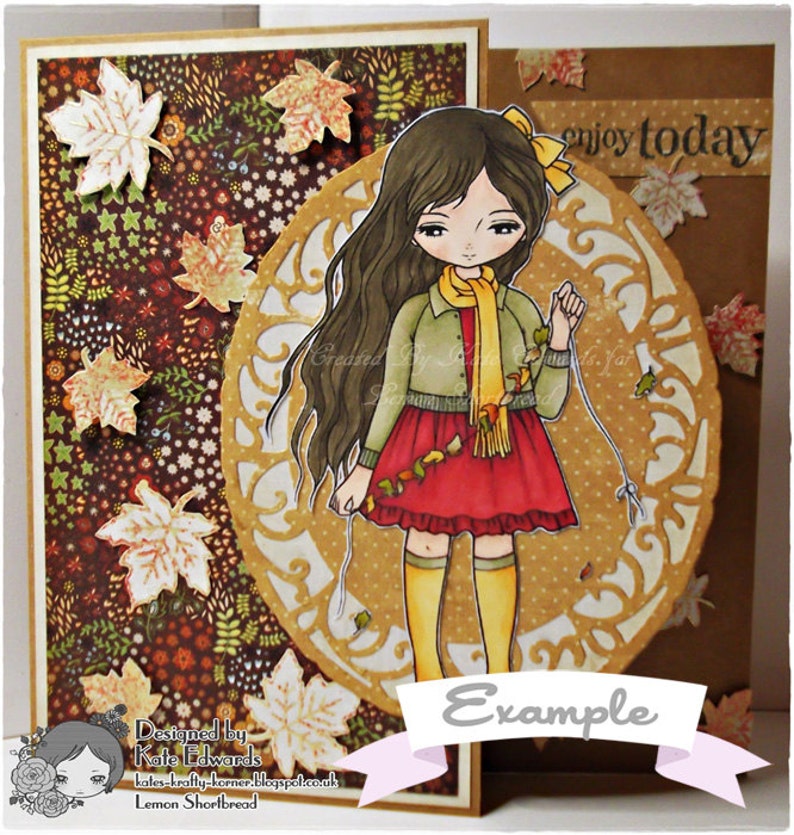 May include: A digital illustration of a girl with long brown hair wearing a red dress and a yellow scarf. She is holding a string of autumn leaves. The background is a brown and gold patterned paper with the text "enjoy today" and "Example".