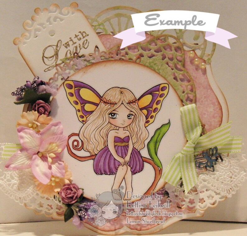 May include: A handmade card featuring a purple fairy with yellow wings and a flower crown. The card is decorated with lace, flowers, and a ribbon. The text "with love" is written on a tag in the upper left corner. The card is designed by Bettina Leikvoll.