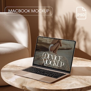 May include: A gold-colored MacBook laptop on a round marble table. The laptop screen displays the text "Device Mockup". The image also includes a cream-colored chair and the text "Macbook Mockup" in a white box.