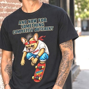 以下が含まれることがあります： 黒いTシャツ。AND NOW FOR SOMETHING COMPLETELY DIFFERENTという文字の下に、モヒカン、赤いヘッドバンド、白いTシャツ、青いズボンを身につけ、黄色いホイールの赤いスケートボードに乗ったフレンチブルドッグのイラストが描かれています。スケートボードにはFRENCHIE AIRと書かれています。