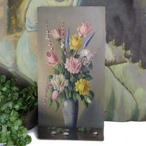 May include: A vintage painting of a bouquet of flowers in a blue and white vase. The flowers are pink, yellow, white, and blue. The painting is signed "Zuckerman".