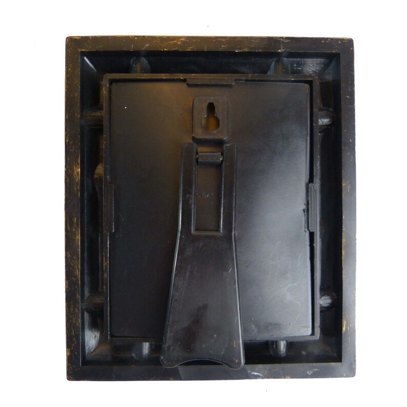 May include: A black picture frame with a stand on the back. The frame has a distressed wood look and a black mat.