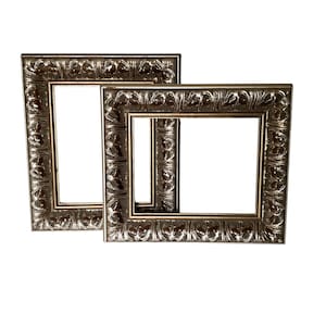 May include: Two rectangular picture frames with a metallic silver finish and a repeating embossed leaf pattern along the border. The frames feature a smooth inner edge and a wider, textured outer moulding, presented in a nested arrangement.