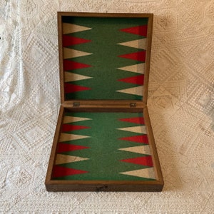 May include: A wooden backgammon game board with a green felt playing surface and red and white triangles. The board is open and ready for play.