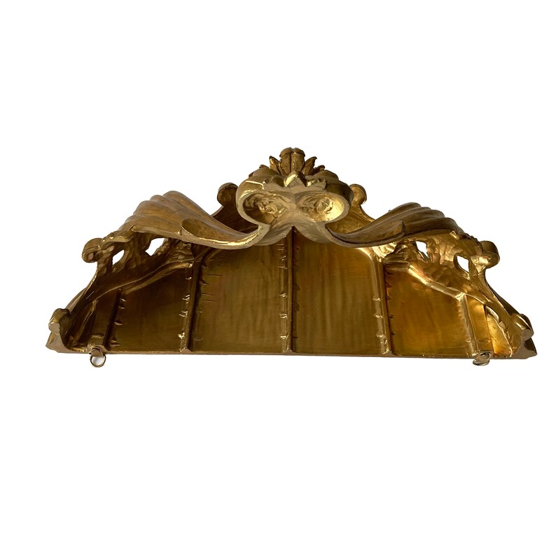 May include: A gold-painted wooden shelf with ornate scrollwork and a decorative top. The shelf is designed to be hung on a wall.