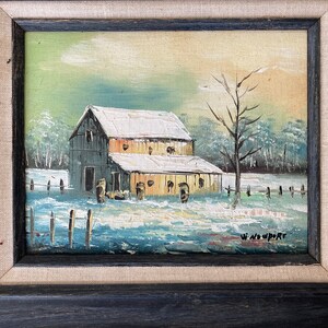 May include: Oil painting of a snow-covered barn with a leafless tree in the foreground. The artwork is framed in a black wooden frame with a linen-textured border. The artist's signature, "W. Newport," is visible in the lower right corner.