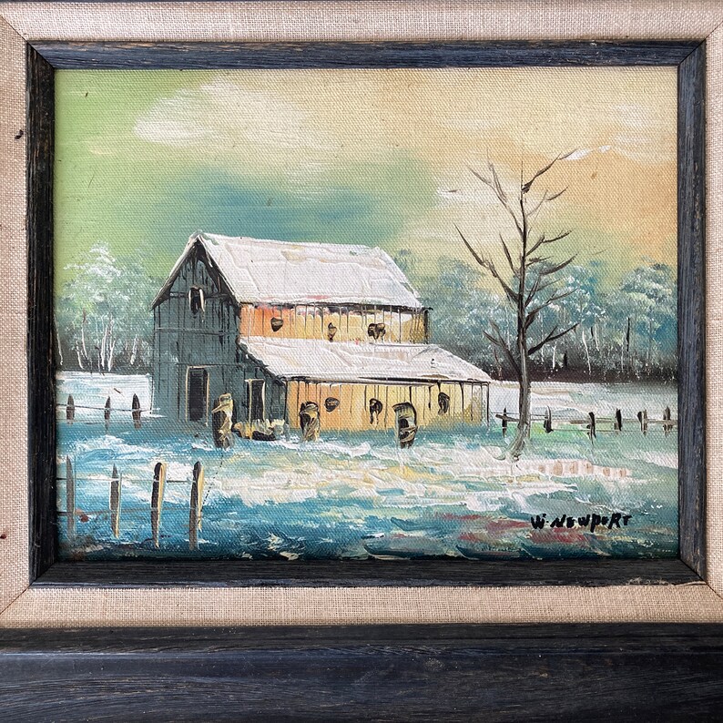 May include: Oil painting of a snow-covered barn with a leafless tree in the foreground. The artwork is framed in a black wooden frame with a linen-textured border. The artist's signature, "W. Newport," is visible in the lower right corner.