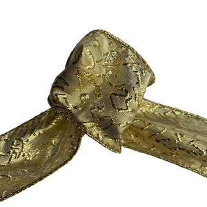 Könnte beinhalten: Nahaufnahme eines goldenen Bandes mit strukturiertem Muster. Das Band ist geknotet, wobei sich die Enden nach rechts erstrecken. Die Kanten des Bandes sind mit einem goldenen Rand versehen. Das Band wird wahrscheinlich zum Geschenkverpacken oder Dekorieren verwendet.