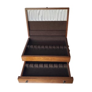 May include: A wooden cutlery chest with a hinged lid and a pull-out drawer. The chest is lined with brown felt and has compartments for storing silverware.