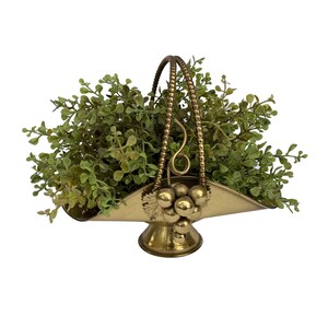 May include: A gold-toned metal fruit basket with a grape design and a beaded handle. The basket is filled with artificial greenery.