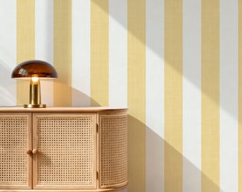 May include: A wooden cabinet with two doors featuring a woven cane texture and rounded edges. A mushroom-shaped lamp with a dark brown glass shade sits on top. The background is a wall covered in vertical yellow and white striped wallpaper.