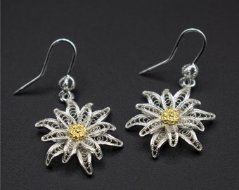 May include: A pair of silver filigree earrings with a gold center, shaped like a flower.