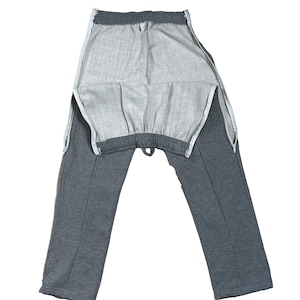 Może przedstawiać: Szare spodnie dresowe z bocznymi zamkami błyskawicznymi i sznurkiem w pasie.
