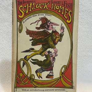 May include: A vintage book titled "The Incredible Schlock Homes" by Robert L. Fish. The cover features a whimsical illustration of two cartoonish figures in a detective theme, with text in red and yellow. The book is displayed on a clear stand.