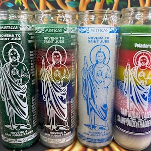 May include: Four glass prayer candles with labels featuring an illustration of Saint Jude. The candles are green, red, white, and rainbow-colored, with text that reads "Novena to Saint Jude" and "San Judas Tadeo".