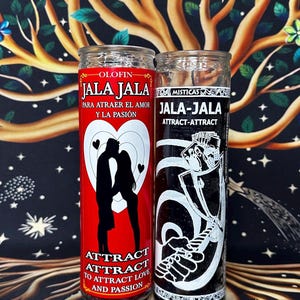 May include: Two cylindrical glass candles. The left candle is red with a white heart graphic, a silhouette of a couple, and text reading OLOFIN JALA JALA PARA ATRAER EL AMOR Y LA PASIÓN ATTRACT ATTRACT TO ATTRACT LOVE AND PASSION. The right is black with white text.