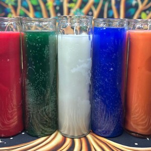 May include: A collection of seven tall, cylindrical candles in glass jars. The candles are various colors, including pink, red, green, white, blue, orange, and black. Each candle has a smooth, solid color.