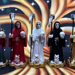 May include: Five Grim Reaper figurines in gold, red, white, black, and rainbow hues. Each figure holds a scythe and a skull-shaped orb, with an owl at the base. The background features a tree design.