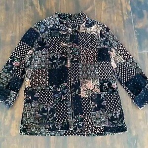 May include: A patchwork jacket in a variety of dark colors, including black, navy, and brown. The jacket features a mix of floral, polka dot, and geometric patterns. It has long sleeves, a mandarin collar, and two front pockets.
