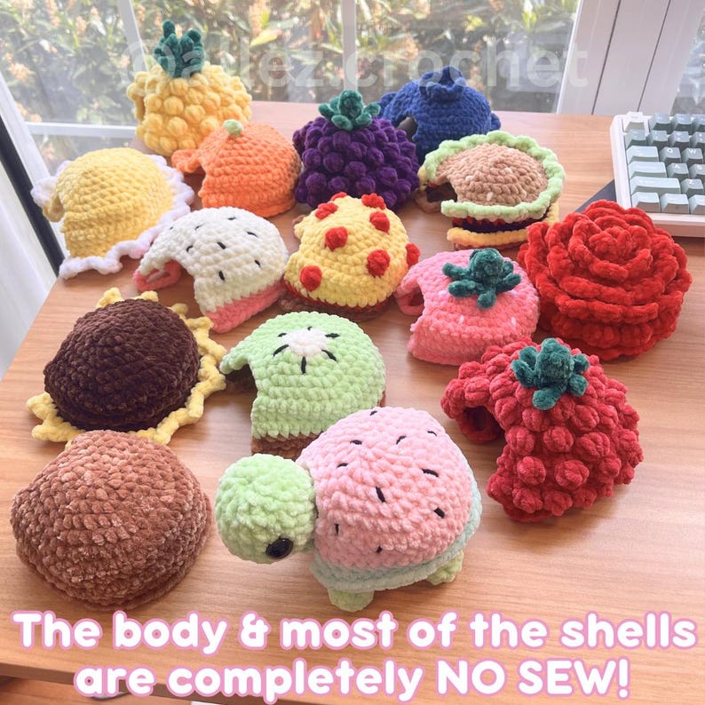May include: A collection of small, plush, crocheted items shaped like various fruits, flowers, and a turtle. The items feature textures resembling pineapples, strawberries, kiwis, and sunflowers in vibrant colors. Text on the image reads: The body & most of the shells are completely NO SEW!