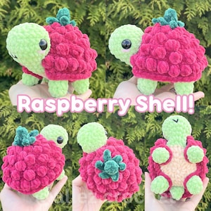 May include: A crochet turtle plush toy featuring a light green head and limbs with a textured, dark pink raspberry-shaped shell topped with a small green leaf. The shell has a bumpy, berry-like surface. The text Raspberry Shell! is visible.