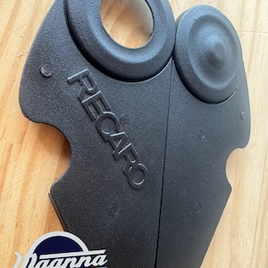 Puede incluir: Piezas de moldura de asiento de coche de plástico negro con la palabra "RECARO" en relieve. Las piezas tienen una superficie texturizada y una abertura circular. El logotipo "Magnna 3D" está en la esquina inferior izquierda.
