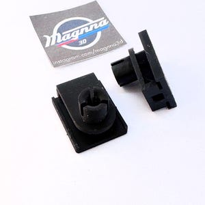 Pode incluir: Duas presilhas de plástico preto com uma base retangular e um poste cilíndrico. As presilhas estão ao lado de um adesivo branco com o texto "Magnna 3D" e o nome de usuário do Instagram "instagram.com/magnna3d".