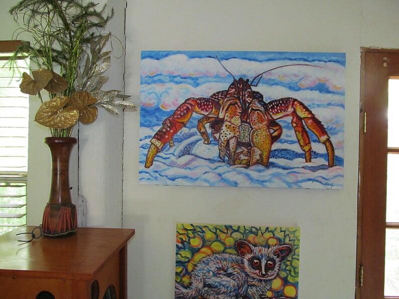 May include: A painting of a large red and yellow crab on a blue and white background. The crab is walking on a sandy beach. The painting is framed and hanging on a white wall.