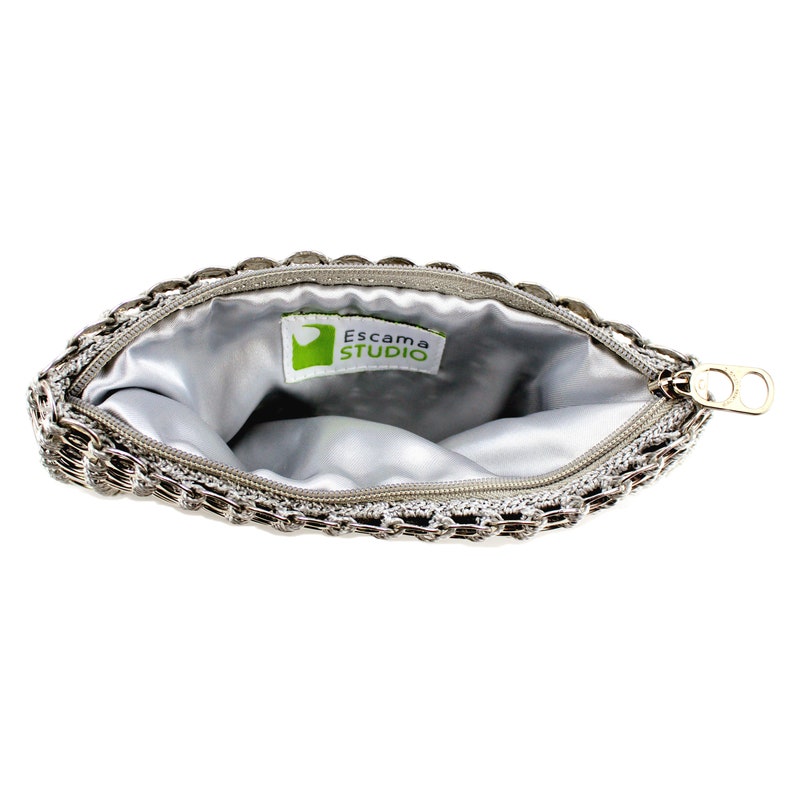 alt= silver pop tab clutch by escama studio with zipper opened to show the detail of the silver fabric liner inside