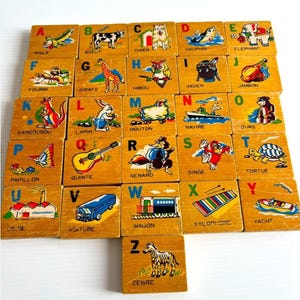 Peut inclure: Ensemble de blocs d'alphabet en bois vintage, chacun avec une lettre et une illustration. Les blocs présentent diverses couleurs et représentent des animaux, des objets et des scènes.