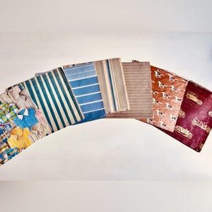 Peut inclure: Une collection de six échantillons de tissu rectangulaires disposés en éventail. Les motifs incluent un imprimé de chemise à carreaux multicolores, des rayures verticales bleues et blanches, des rayures horizontales bleues, des rayures verticales beige, des lignes horizontales brunes et un imprimé brun avec des voitures anciennes.